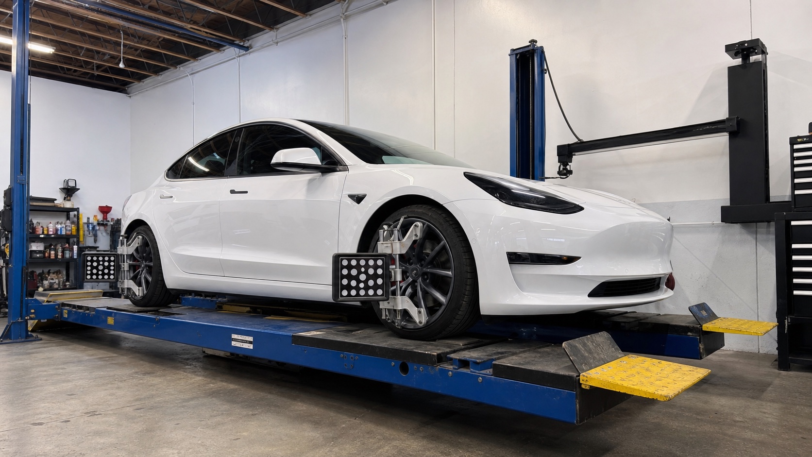 White Tesla Model 3 on a four-wheel alignment rack